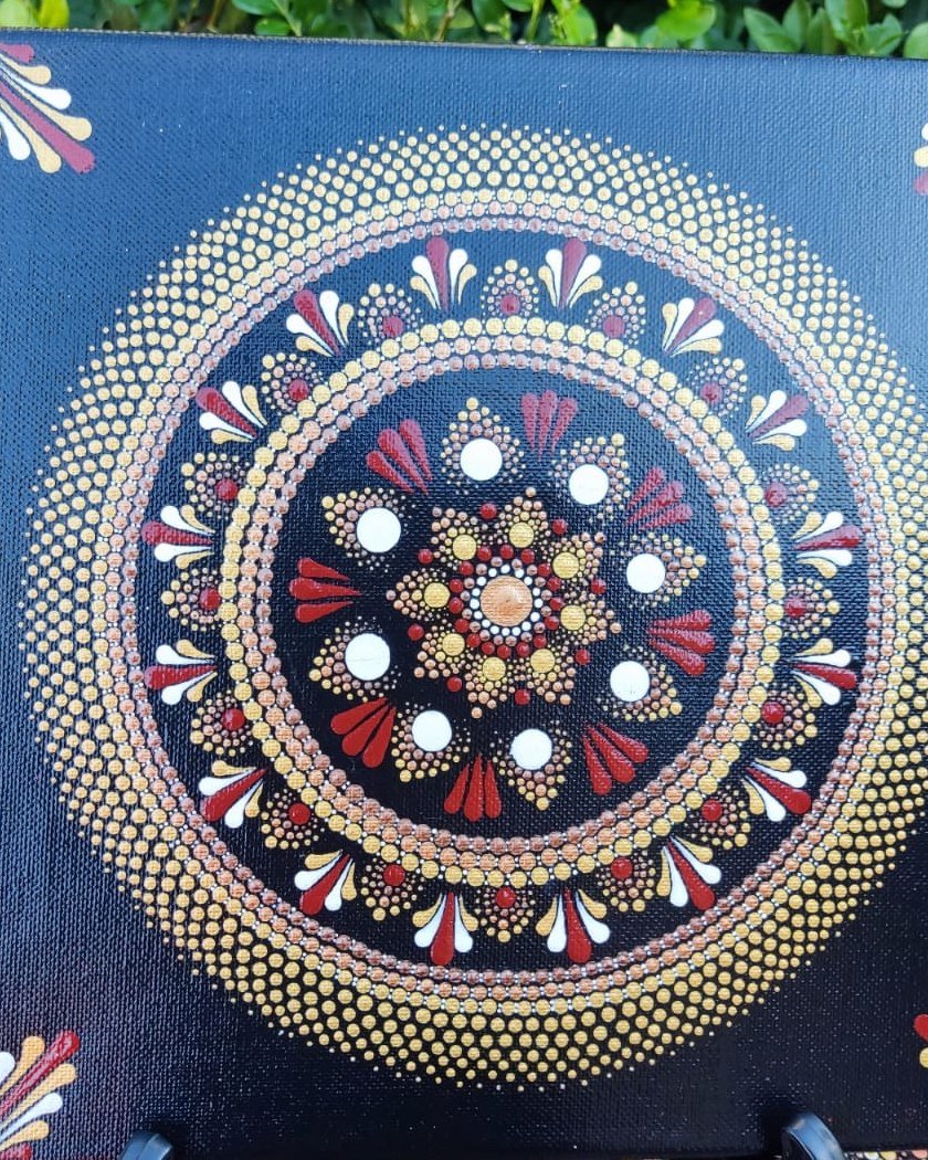 Hand-painted red and gold dot mandala on black canvas by Nadine
